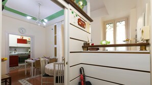 A dining area with a table set for four, a kitchen in the background, and a decorative mirror above the sink. - Anthony 47 (Rome)