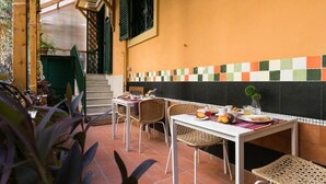 An outdoor dining area with wicker chairs and a table set for breakfast. - Anthony 47 (Rome)
