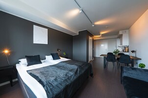 Una habitación de hotel moderna con una cama grande, un escritorio y una zona de comedor.