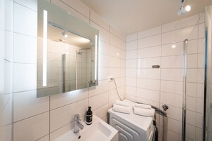 Un baño moderno con un espejo grande, un lavabo, una ducha y una bañera.