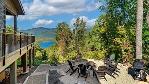 Eine Terrasse mit Sitzgelegenheit und Grill, mit Blick auf einen See und Berge.