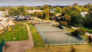 Ein Tennisplatz, umgeben von Wohnhäusern und einem Spielplatz.