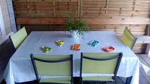Een tafel met een witte tafelkleed, vier stoelen en een potplant.