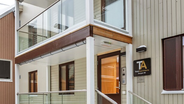 A multi-story residential building with a glass balcony, a metal staircase, and a sign indicating it's a Total Apartments property. - 70 Degrees North Apartment (Tromsø)