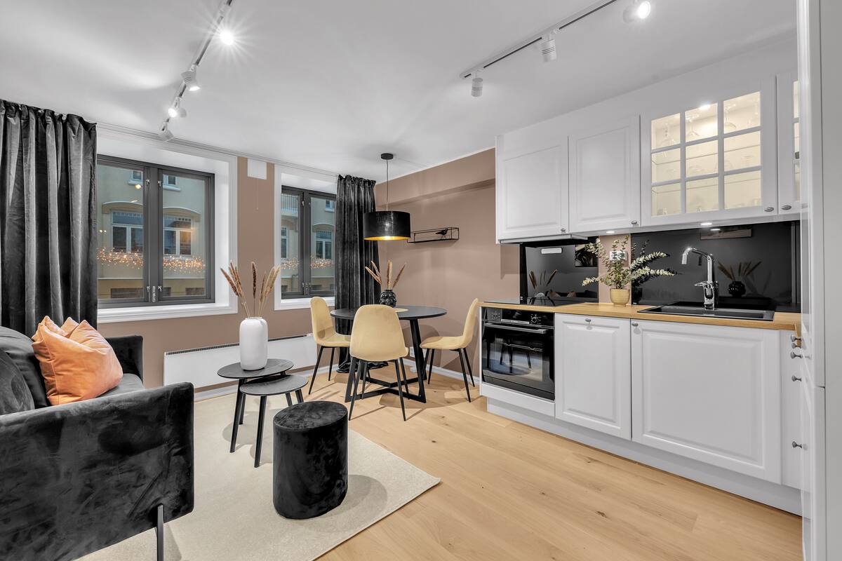 A modern kitchen with white cabinets, a black countertop, and a dining area with a round table and chairs.