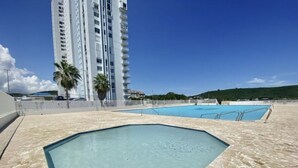 Una piscina sul tetto con superficie d'acqua cristallina e blu, circondata da un solarium in pietra.
