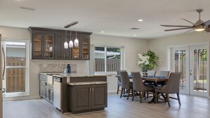A modern kitchen with dark cabinetry, a central island, and pendant lighting.