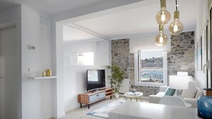 Ett modernt vardagsrum med TV, en matplats och utsikt över havet.