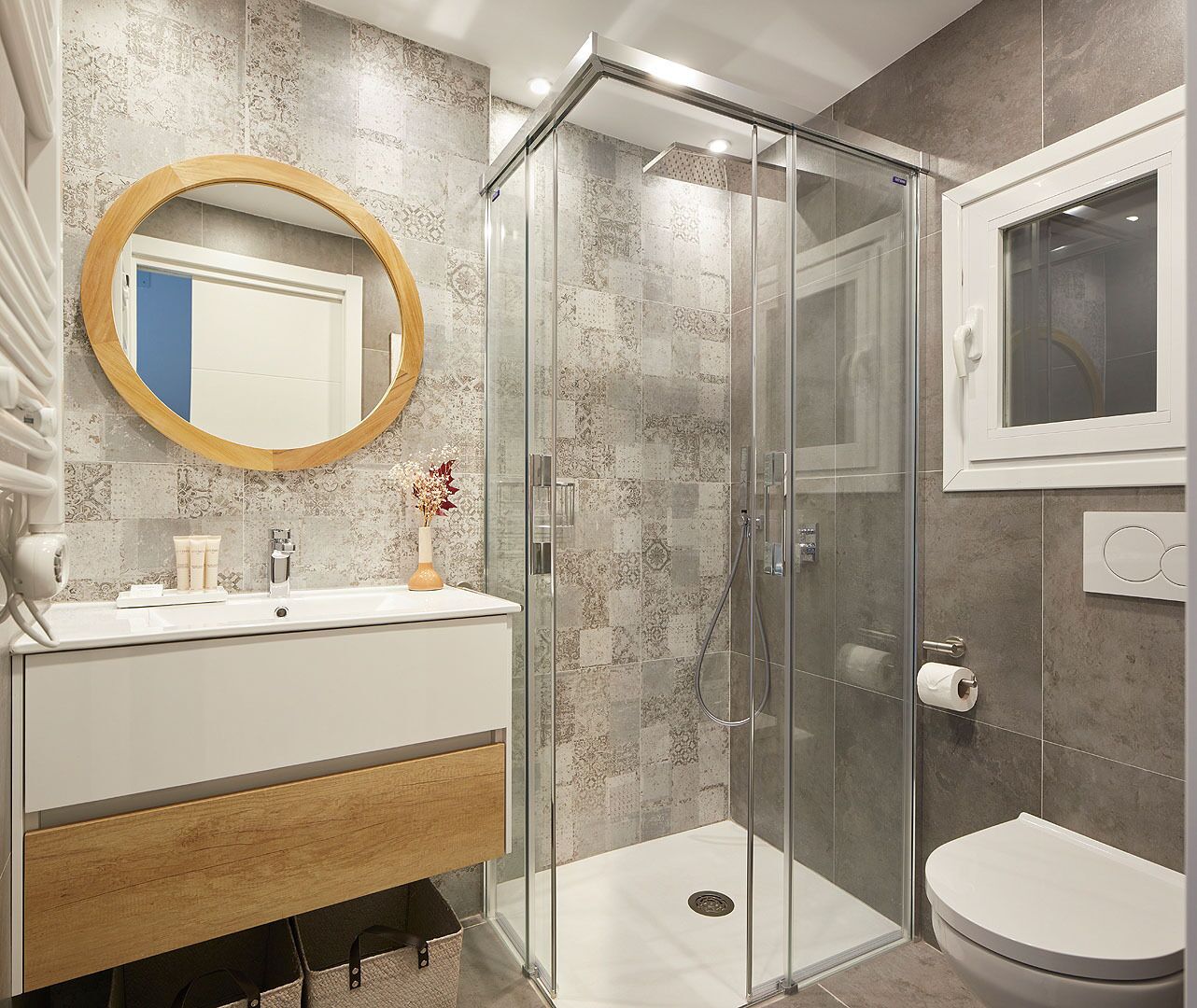 A modern bathroom with a glass-enclosed shower, a round mirror, and a white toilet.