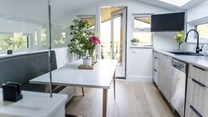 Een moderne keuken met een groot raam, een eethoek met een tafel en een geïntegreerde vaatwasser.