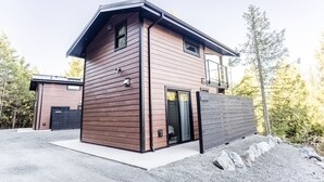 Een modern huis met twee verdiepingen, een houten gevel, een garage en een oprit.