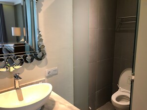 A bathroom with a white sink, a mirror with a decorative frame, and a toilet.