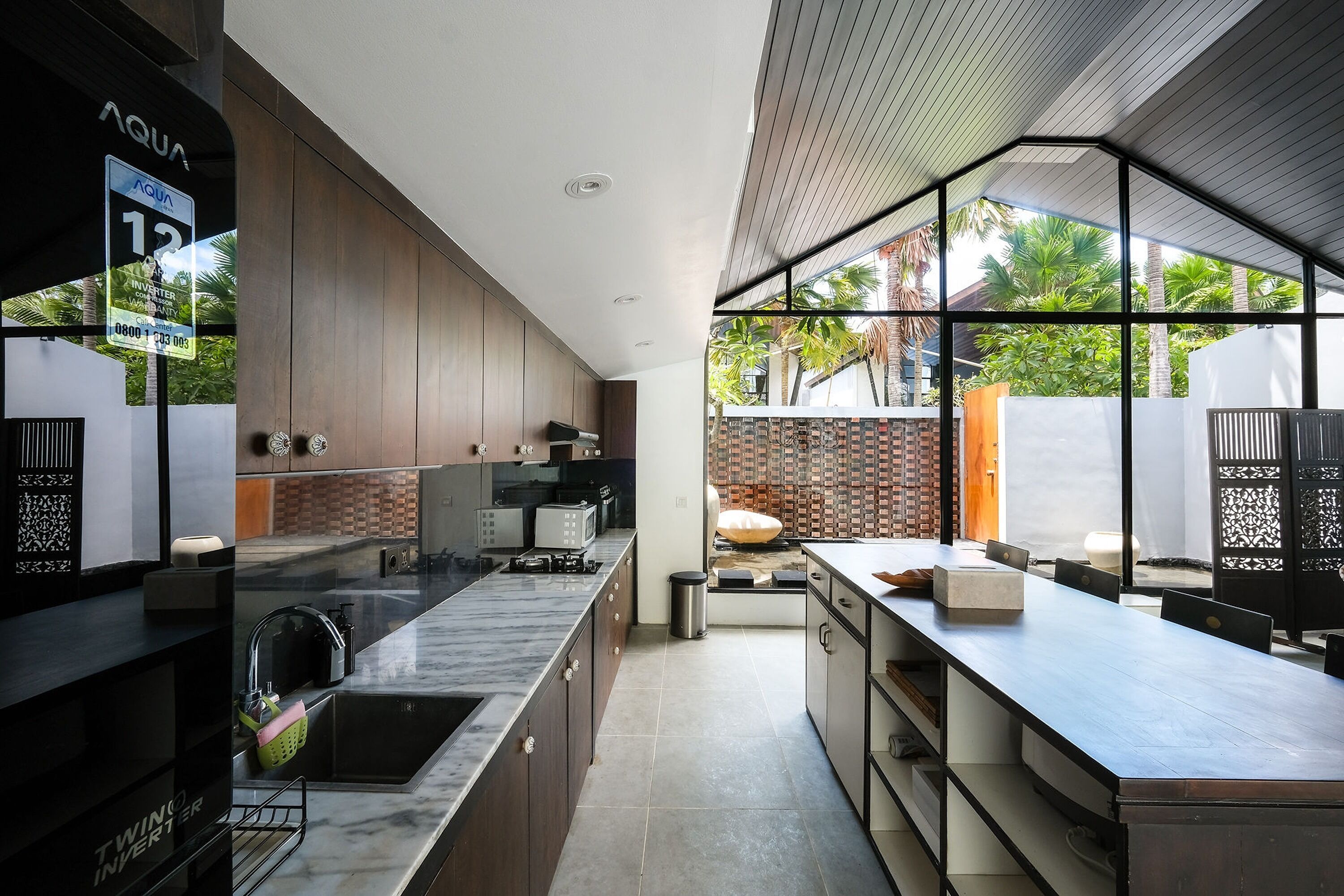 A modern kitchen with a large island, built-in appliances, and a view of the outdoors.