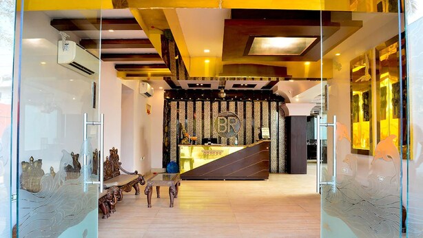 Un área de recepción con diseño moderno, que incluye un mostrador de recepción, un espacio de espera con sillas y una pared decorativa con un logotipo.