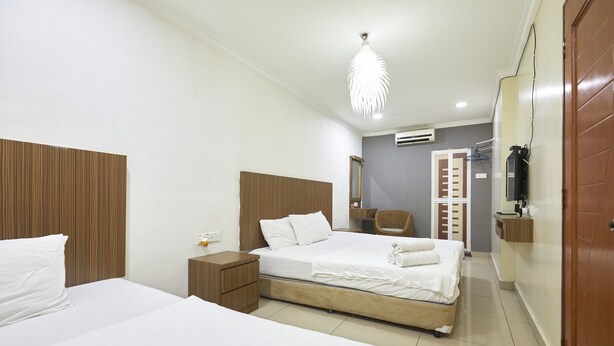 A hotel room with two beds, a wooden headboard, a nightstand, a chair, a wardrobe, and a television. - Hotel Pritty (Kuala Lumpur)