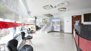 A hotel lobby with a reception desk, a staircase, and a seating area with chairs. - Hotel Pritty (Kuala Lumpur)