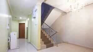 A hallway with a staircase, a door, and a water dispenser. - Hotel Pritty (Kuala Lumpur)