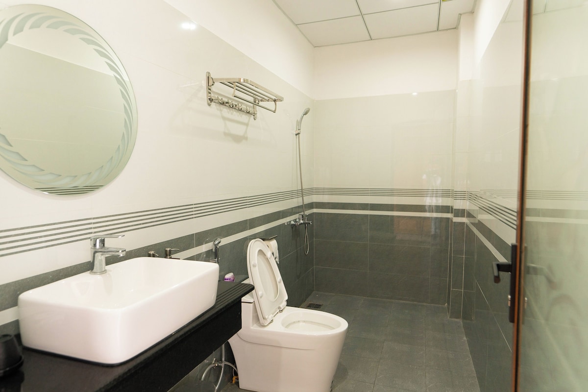 A bathroom with a white sink, a toilet, a shower, and a mirror.