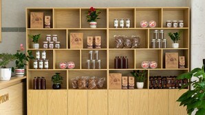 Un estante de madera con diversos productos envasados, incluyendo frascos y bolsas, probablemente para la venta o exhibición.