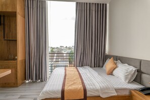 Quarto de hotel com uma cama grande, um guarda-roupa de madeira e vista para a cidade pela janela.