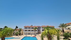 Ein Hotel mit Schwimmbad, Palmen und blauem Himmel.