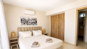 Ein Hotelzimmer mit einem großen Bett, einem Holzschrank, einer Wandklimaanlage und einem gerahmten Kunstwerk über dem Bett.