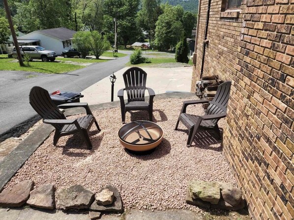 Une terrasse avec quatre fauteuils Adirondack, un foyer et un mur en briques.