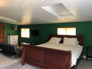 A bedroom with a wooden bed, green walls, a desk, and a chair.
