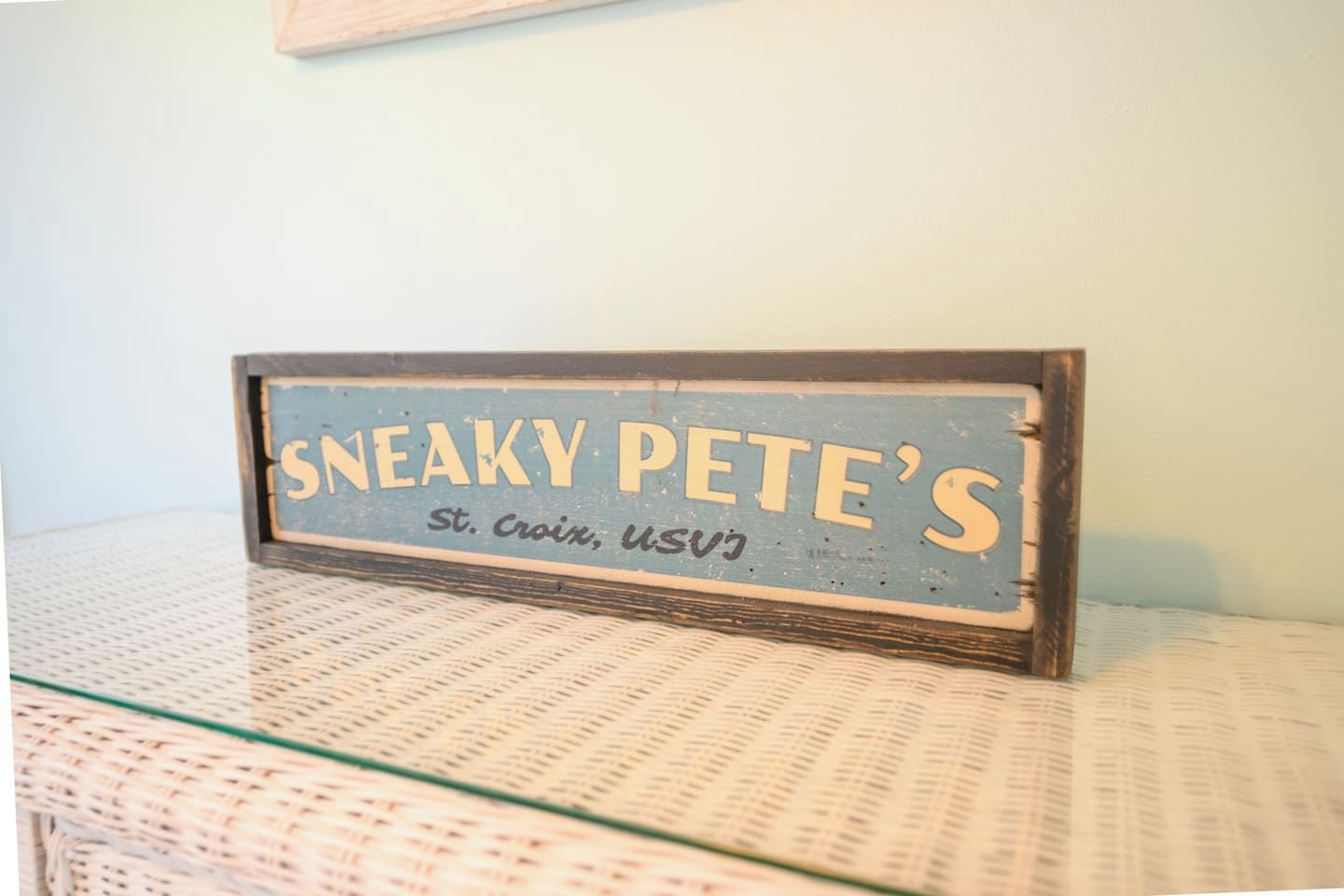 A vintage sign with the text 'SNEAKY PETE'S' and 'St. Croix, USVI' on a textured surface.