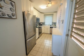 A kitchen with white cabinets, a stainless steel refrigerator, a tiled floor, and a ceiling fan. - 3-bedroom condo w/ amazing Ocean views! (Christiansted)