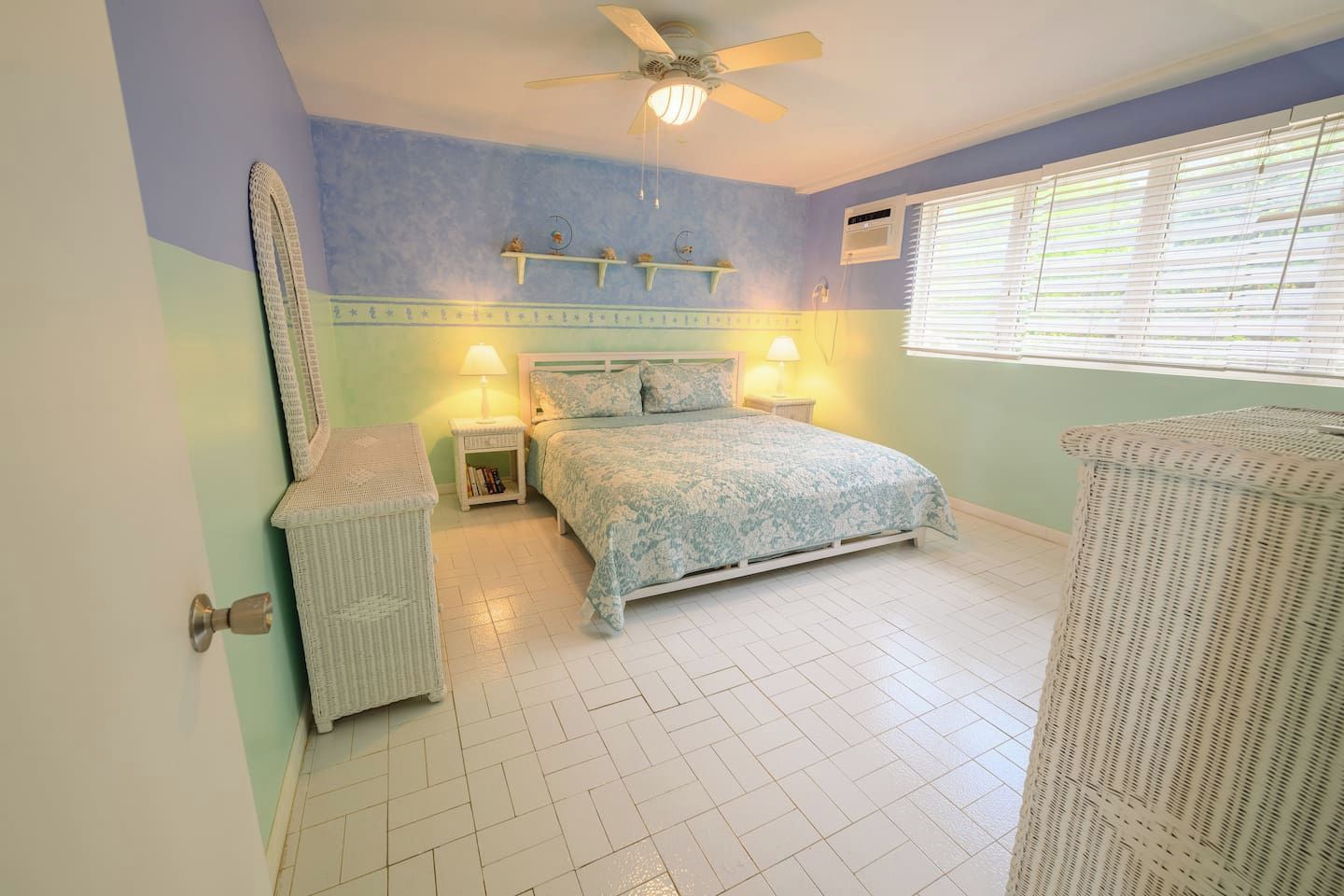 A bedroom with a bed, bedside tables, a ceiling fan, and a window with blinds.