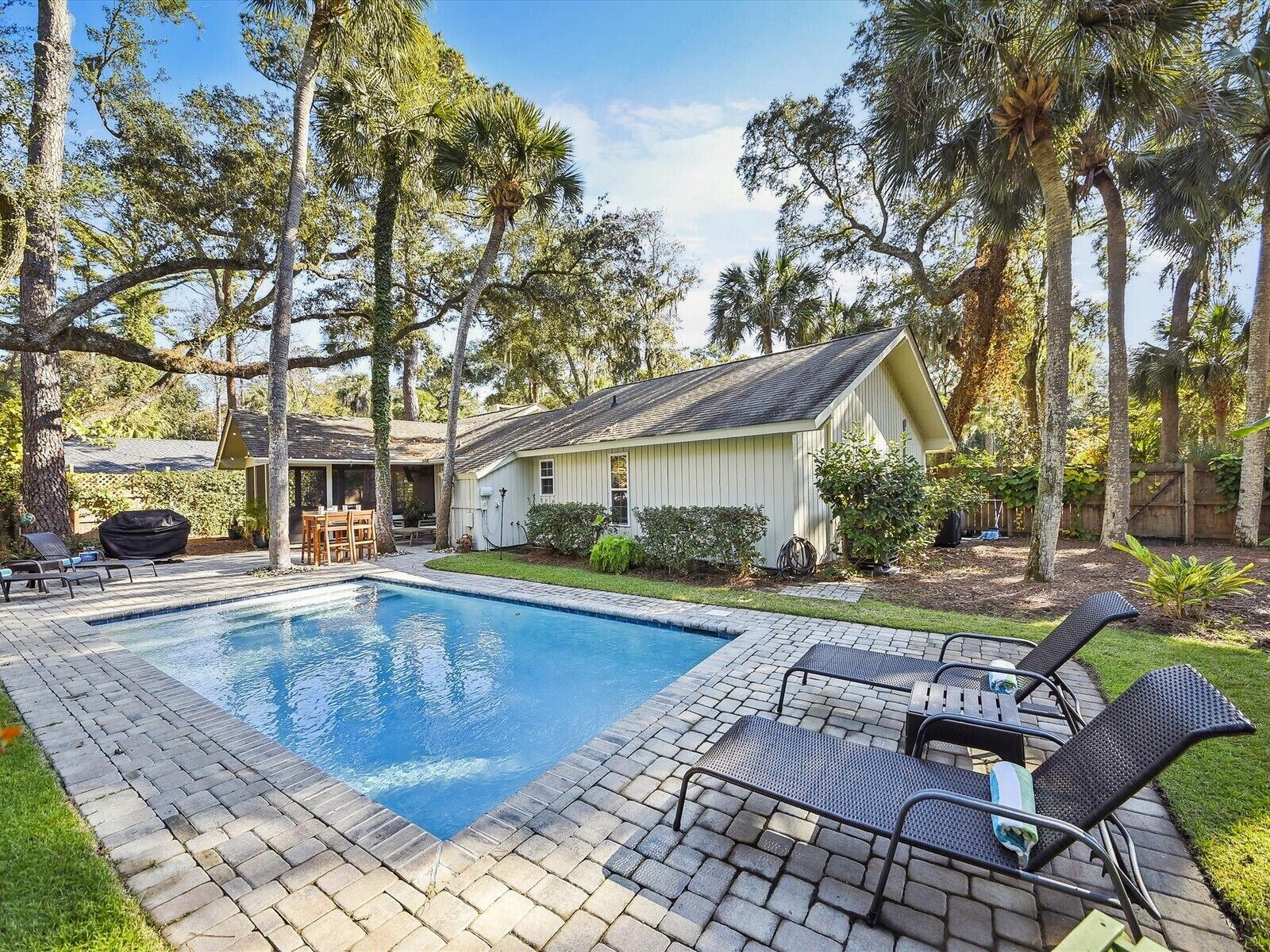 A backyard with a swimming pool, lounge chairs, and a shed.