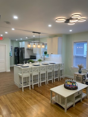 A modern kitchen with white cabinetry, a central island with seating, and a dining table set for four.