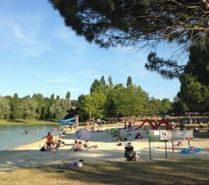 Um parque à beira do lago com áreas para piquenique, uma área de natação e um parquinho.