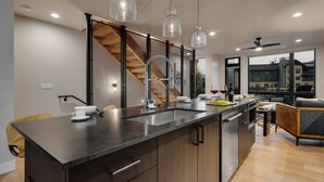 A modern kitchen with a large island, stainless steel appliances, and a dining area with a view of the city. - Luxurious + Hot Tub on Rooftop Deck + Close to Skiing - Borough House (Steamboat Springs)