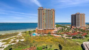 A high-rise hotel with a pool, beachfront view, and a well-maintained garden area.