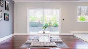 A spacious room with hardwood flooring, a central white table with a plant, and a large sliding glass door leading to a garden. - Maison du Lavande, artzy 4Br House, gateway 2 Napa (Vallejo)