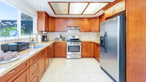 A modern kitchen with wooden cabinets, stainless steel appliances, and a large window providing a view of the outdoors. - Maison du Lavande, artzy 4Br House, gateway 2 Napa (Vallejo)