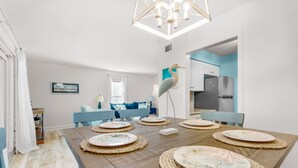 A dining area with a wooden table set for six, surrounded by blue chairs.