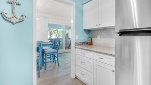 A kitchen with white cabinets, a stainless steel refrigerator, and a dining area with blue chairs and a table.