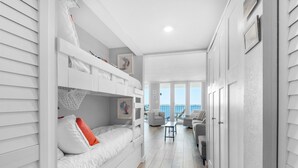 Un dormitorio moderno y bien iluminado con literas, una mesita pequeña y vistas al balcón.