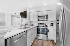 A modern kitchen with white cabinetry, stainless steel appliances, a built-in oven, and a microwave.