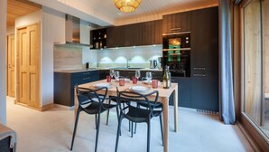 Una cocina moderna con armarios oscuros, una mesa de comedor de madera y sillas negras.