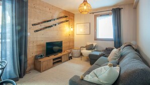 Una sala de estar acogedora con pared de madera, televisor, sofá y un soporte para esquíes.