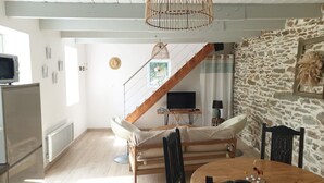 Uma sala de estar aconchegante com sofá, mesa de jantar, televisão e parede de pedra.