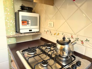 Una cocina con estufa a gas, electrodoméstico Whirlpool y un salpicadero decorativo.