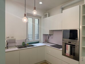 A modern kitchen with white cabinets, a stainless steel oven, a built-in microwave, and pendant lighting. - Anthony House Via Villafranca (Rome)