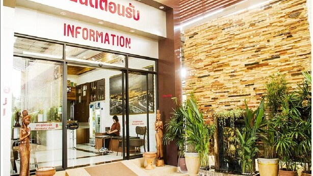 A hotel entrance with a sign in a foreign language, a reception desk, and potted plants outside. - Bander Hotel (Phu Khiao)