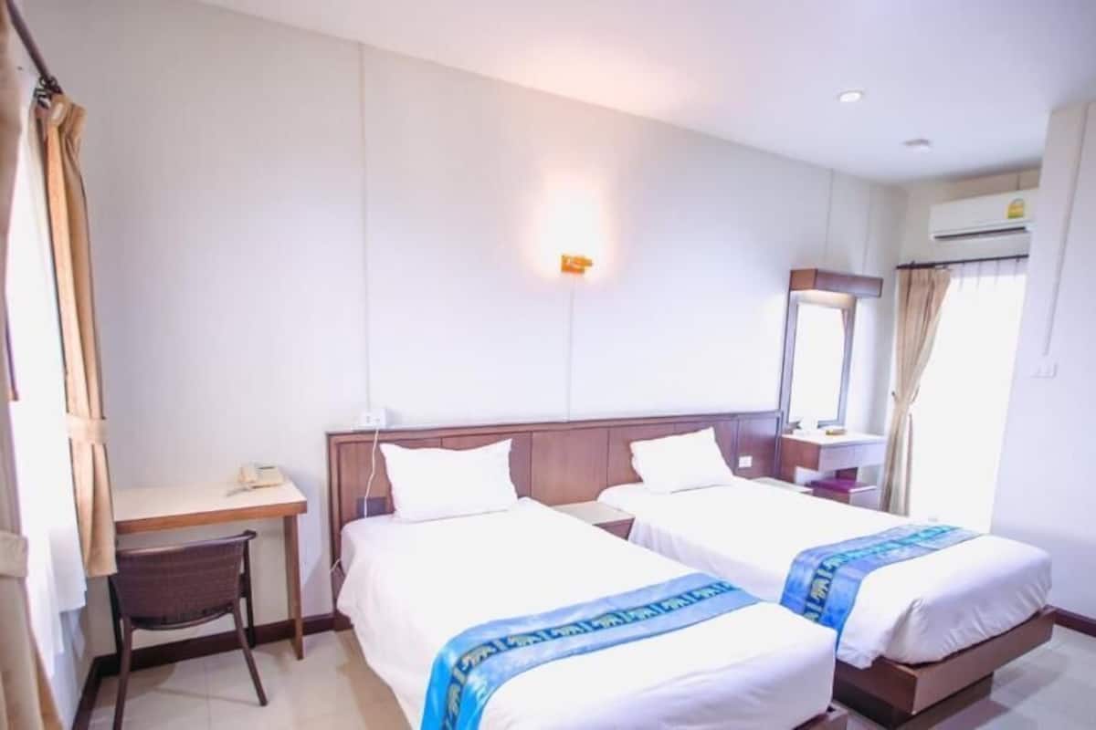 A hotel room with two beds, a desk, and a chair.