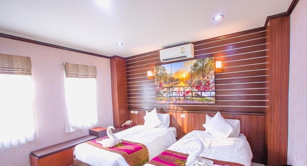 Een hotelkamer met twee bedden, een schilderij aan de muur en een airconditioning.